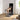 Woman kneels on a connected home gym and extends one leg against cable resistance.