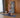 A woman follows a trainer on a tall fitness display while holding a stretch at home.