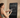 Woman adjusting workout settings on a smart mirror touchscreen while holding a phone.