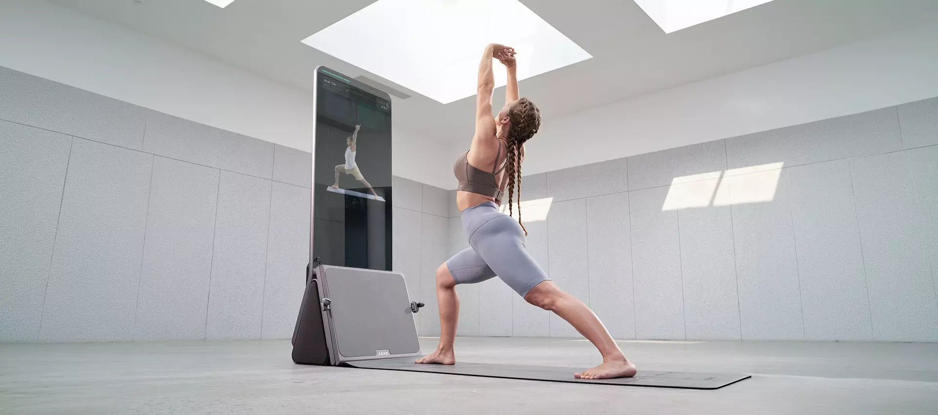 Woman holding a lunge beside a fitness screen in a home workout space