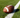 An American football resting on a lush green field next to a crisp white yard line.