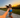 A woman in athletic gear wearing headphones while running along a path at sunset.